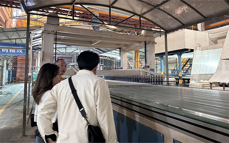 พนักงานโรงงานจีนอธิบายกระบวนการผลิตหินให้กับลูกค้าต่างชาติ